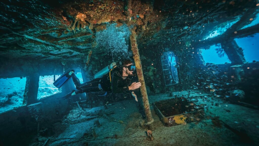 scuba diver exploring inside a military shipwreck